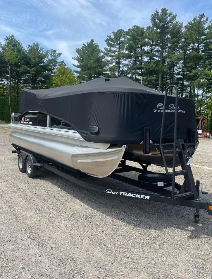 Slide: The Image of 2025 Sun Tracker SportFish 20 DLX pontoon boat on trailer, covered, parked outdoors. - 3
