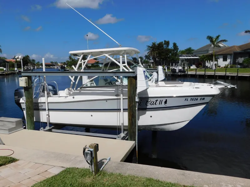 Slide: The Image of 2020 World Cat 230 DC boat docked by a canal under a clear blue sky. - 0