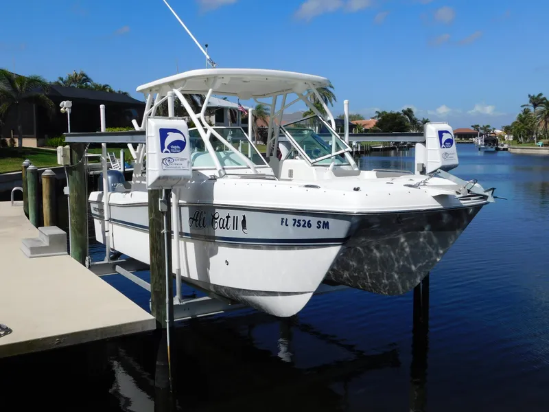 Slide: The Image of 2020 World Cat 230 DC boat docked on a sunny day, featuring a sleek white design. - 1