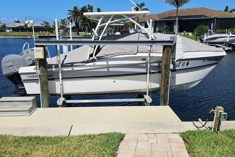 Slide: The Image of 2020 World Cat 230 DC boat docked on a lift by a waterfront property. - 2