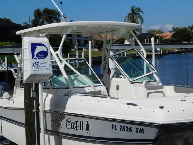 Slide: The Image of 2020 World Cat 230 DC boat docked by waterfront with palm trees in background. - 38