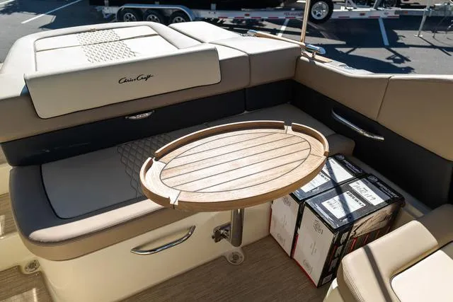 Slide: The Image of 2025 Chris-Craft 25 Sportster interior with wooden table and cushioned seating. - 10