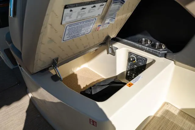 Slide: The Image of Open storage compartment in 2025 Chris-Craft 25 Sportster boat, featuring control panel and cup holders. - 13