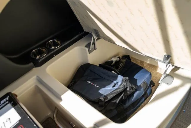 Slide: The Image of 2025 Chris-Craft 25 Sportster storage compartment with backpack and cup holders. - 19