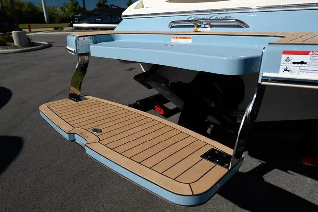 Slide: The Image of 2025 Chris-Craft 25 Sportster swim platform, light blue and wood finish, parked outdoors. - 3