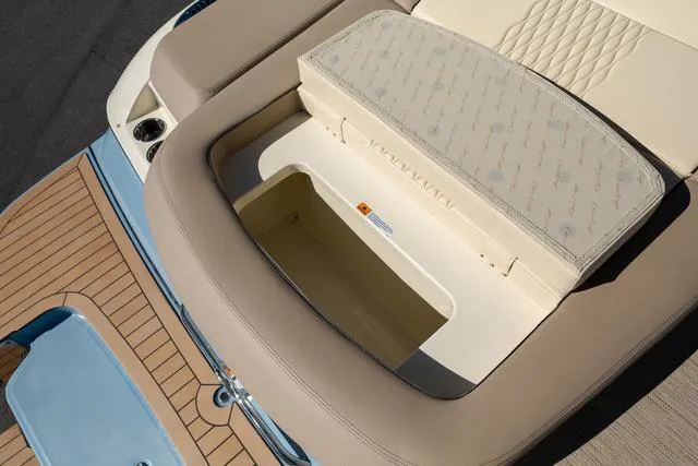 Slide: The Image of 2025 Chris-Craft 25 Sportster boat with open storage compartment, beige and blue interior. - 7