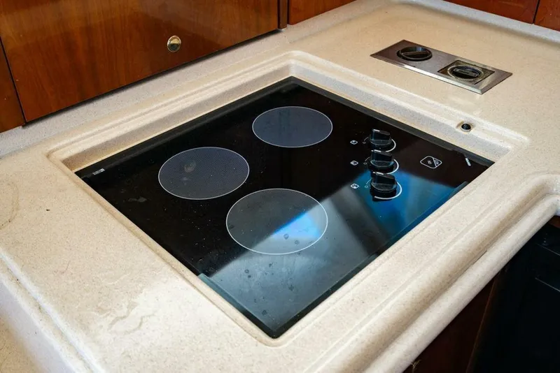 Slide: The Image of Stovetop in 1999 Sea Ray 56 Sedan Bridge yacht kitchen, featuring three burners and control knobs. - 11