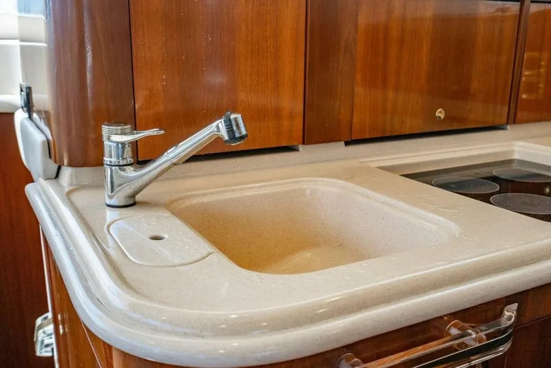 Slide: The Image of 1999 Sea Ray 56 Sedan Bridge kitchen sink with wooden cabinetry and modern faucet. - 12