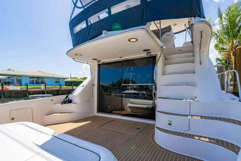 Slide: The Image of 1999 Sea Ray 56 Sedan Bridge yacht with elegant deck and staircase, docked by waterfront. - 25