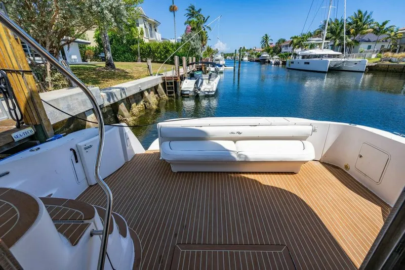 Slide: The Image of 1999 Sea Ray 56 Sedan Bridge yacht deck with seating, docked in a scenic canal. - 26