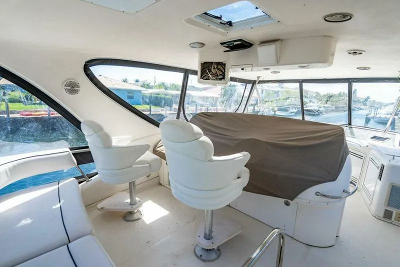 Slide: The Image of 1999 Sea Ray 56 Sedan Bridge interior with white seating and covered helm. - 27