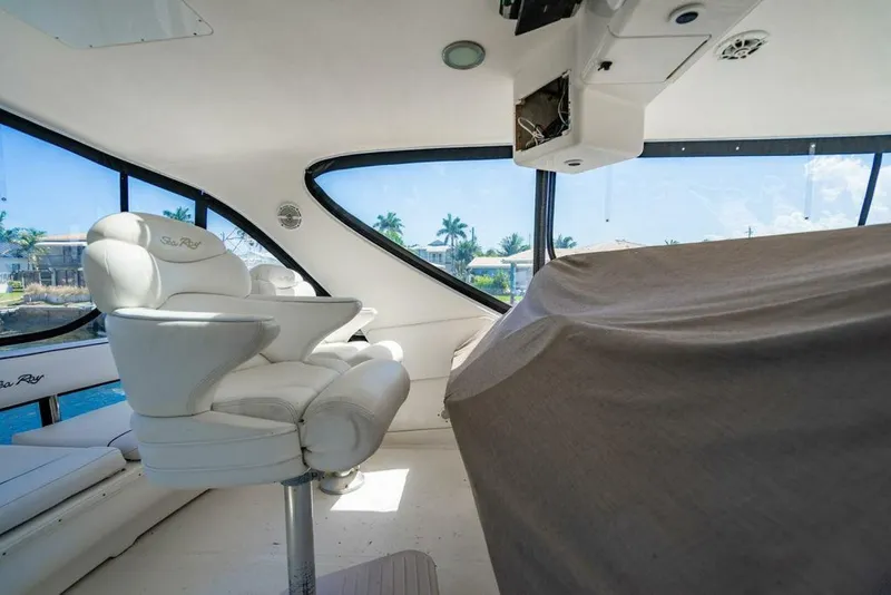 Slide: The Image of 1999 Sea Ray 56 Sedan Bridge interior with captain's chair and covered console, featuring large windows. - 30
