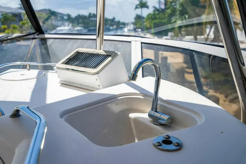 Slide: The Image of 1999 Sea Ray 56 Sedan Bridge yacht sink and faucet on deck, with scenic marina view. - 32