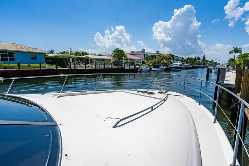 Slide: The Image of 1999 Sea Ray 56 Sedan Bridge yacht on a sunny waterfront, surrounded by houses and palm trees. - 34