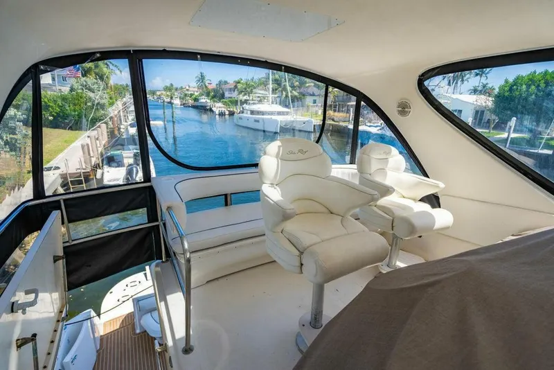 Slide: The Image of 1999 Sea Ray 56 Sedan Bridge interior with white seating and panoramic waterway view. - 4