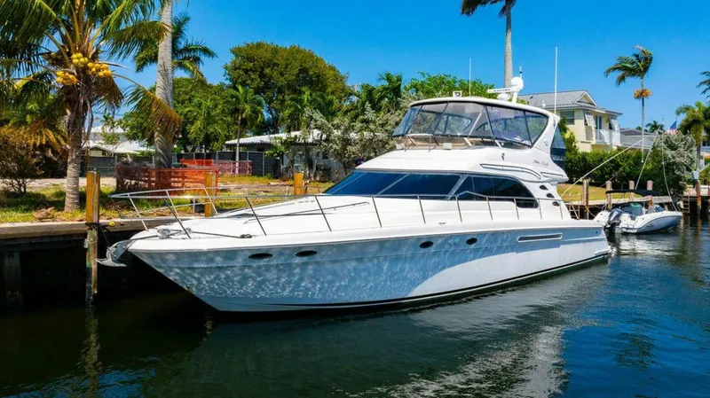 Slide: The Image of 1999 Sea Ray 56 Sedan Bridge yacht docked in a tropical marina setting. - 40