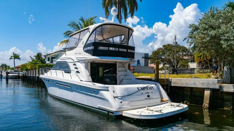 Slide: The Image of 1999 Sea Ray 56 Sedan Bridge yacht docked in a sunny canal setting. - 7
