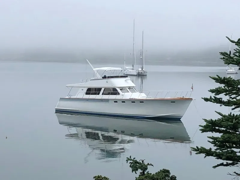 Slide: The Image of 1980 Huckins Sports Cruiser on calm, misty water with distant sailboats. - 1