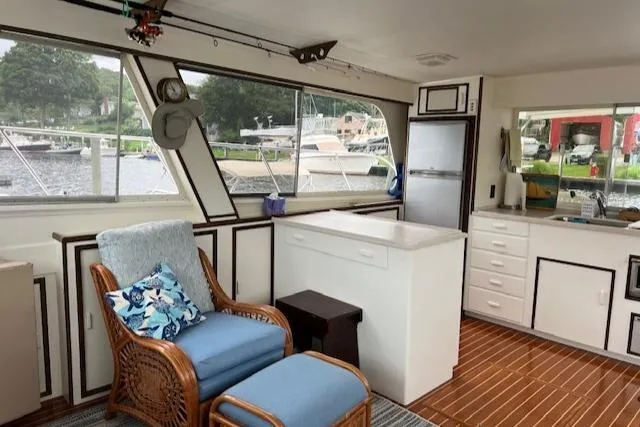 Slide: The Image of Interior of 1980 Huckins Sports Cruiser with wicker chair, kitchenette, and large windows. - 15