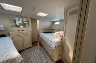 Slide: The Image of 1980 Huckins Sports Cruiser cabin with twin beds, storage, and natural light. - 21