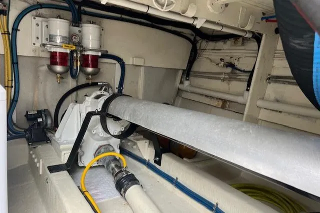 Slide: The Image of Engine room of a 1980 Huckins Sports Cruiser, showcasing mechanical components and piping. - 24