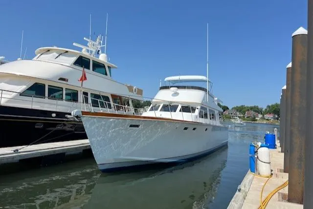 Slide: The Image of 1980 Huckins Sports Cruiser docked at marina under clear blue sky. - 3