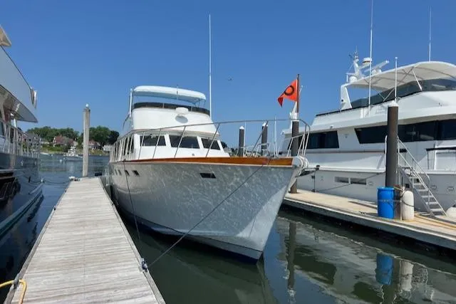 Slide: The Image of 1980 Huckins Sports Cruiser docked at marina, clear blue sky, calm water. - 5