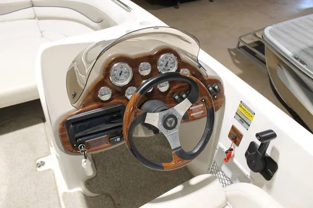 Slide: The Image of Captain's seat on 2005 Kayot V220i boat, featuring white leather upholstery and wooden steering wheel. - 8