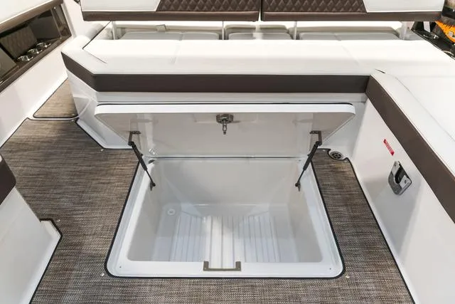 Slide: The Image of 2025 Cobalt R33 boat interior with open storage compartment, featuring cushioned seating and carpeted flooring. - 17