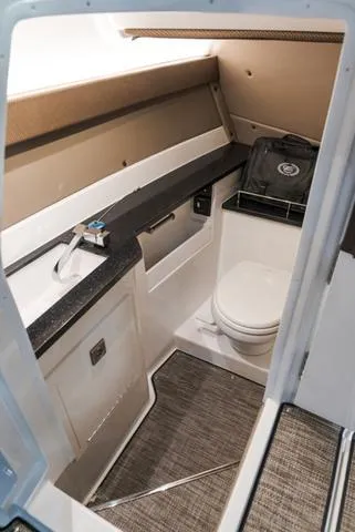 Slide: The Image of 2025 Cobalt R33 boat interior with compact bathroom, featuring a toilet and sink. - 26