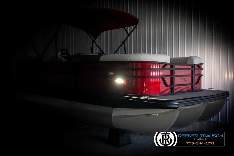 Slide: The Image of 2025 Bennington 22 SSRSE pontoon boat with red exterior and canopy in a dimly lit showroom. - 4