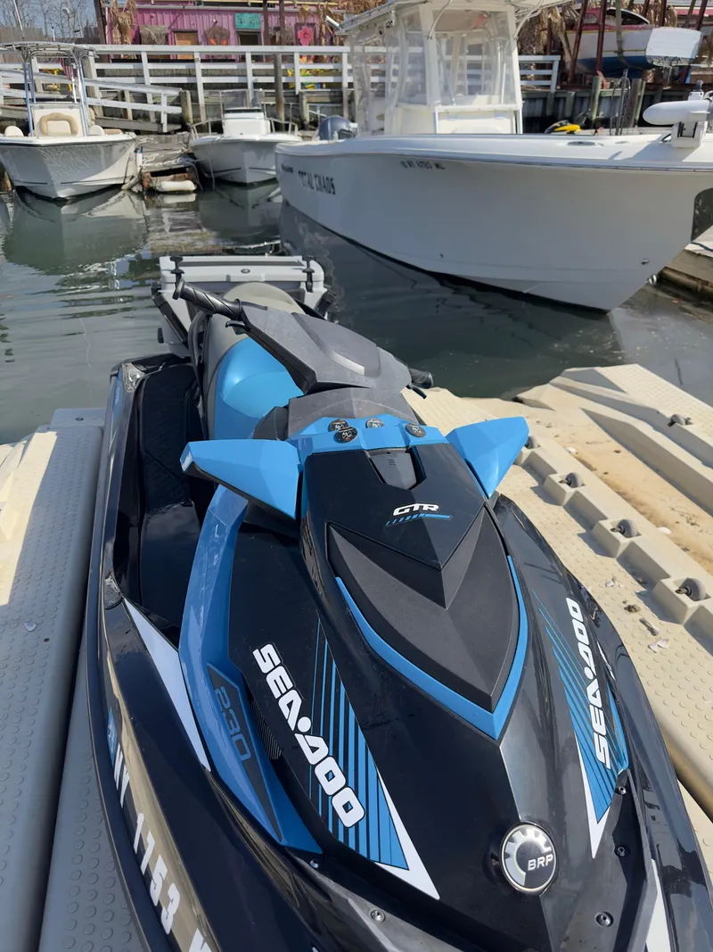 Slide: The Image of 2019 Sea-Doo GTR 230 jet ski docked at a marina, featuring sleek black and blue design. - 6