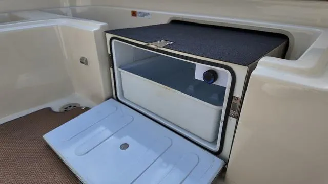 Slide: The Image of 2017 Chris-Craft Launch 27 boat cooler compartment with open lid, showcasing storage space. - 14