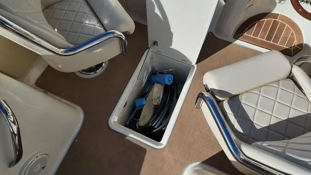 Slide: The Image of 2017 Chris-Craft Launch 27 interior storage compartment with accessories, surrounded by cushioned seating. - 24