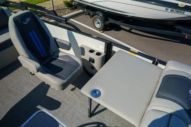 Slide: The Image of 2025 Barletta Corsa 23UC boat interior with seating and table, featuring cup holders. - 19