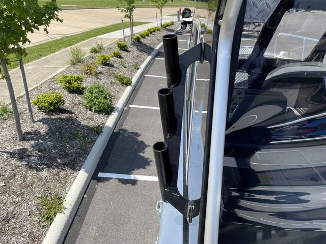 Slide: The Image of 2024 Thunder Jet Alexis OS 22' boat with rod holders, parked in a landscaped area. - 21