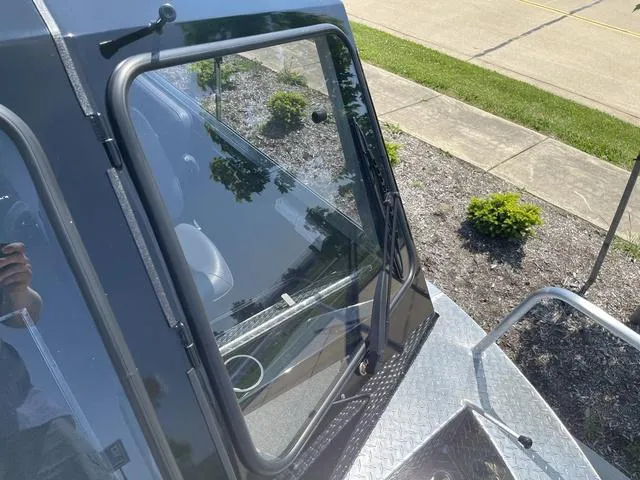 Slide: The Image of 2024 Thunder Jet Alexis OS 22' boat windshield and deck, with greenery in the background. - 43