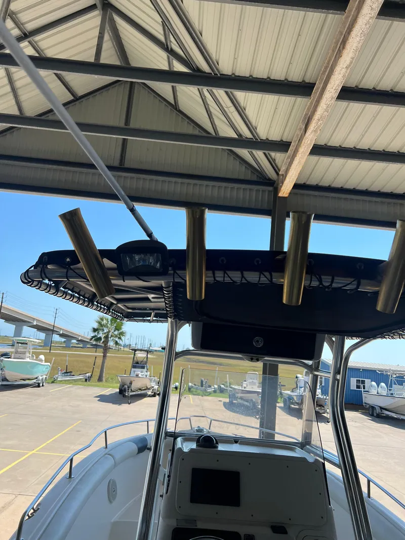 Slide: The Image of 2007 Century 2600 CC boat under a metal roof, featuring rod holders and console. - 13
