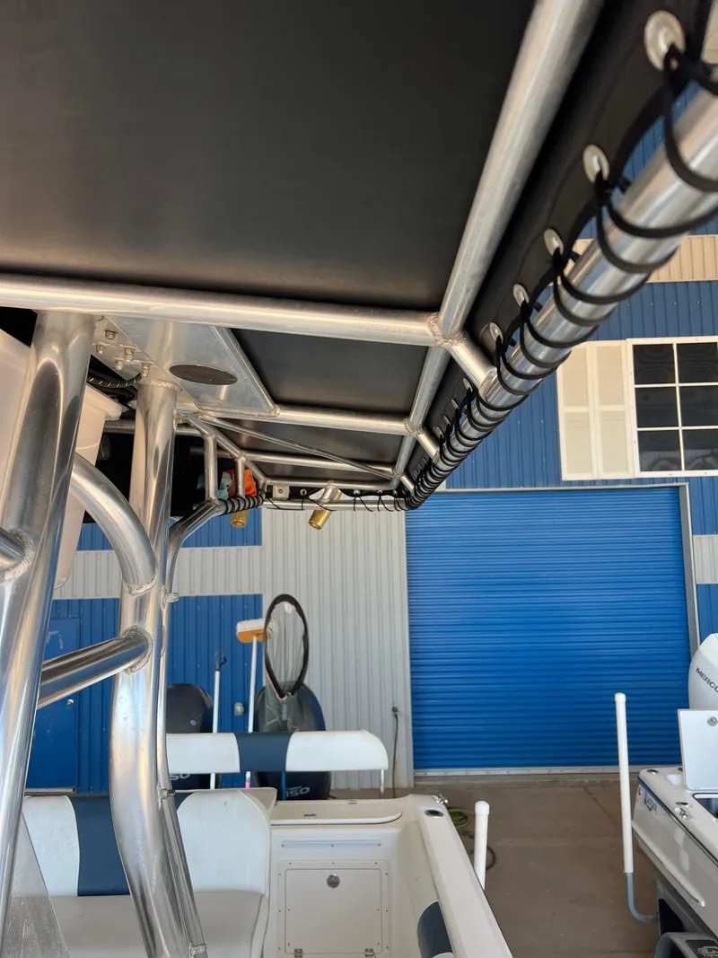 Slide: The Image of 2007 Century 2600 CC boat with T-top and rod holders, docked near blue building. - 15