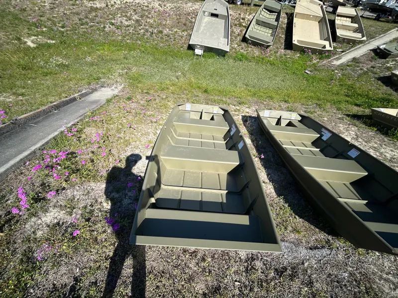 Slide: The Image of 2025 Crestliner CR1240 boats displayed outdoors on grass with purple flowers nearby. - 8