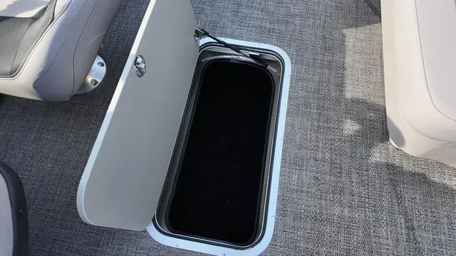 Slide: The Image of 2025 Barletta Aria A22CC boat storage compartment with open hatch on carpeted floor. - 13