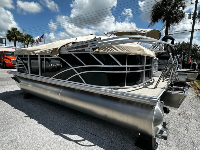 Slide: The Image of 2025 Sylvan Mirage 8520 LZ pontoon boat with sleek design, parked outdoors under a cloudy sky. - 2