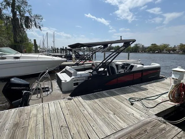 Slide: The Image of 2023 Barletta CORSA 23 UA pontoon boat docked by a scenic waterfront. - 4