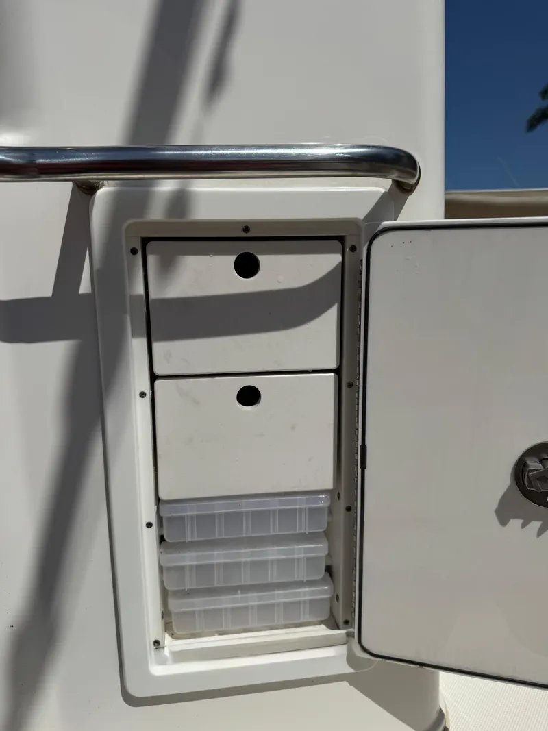 Slide: The Image of 2018 Key West Billistic 281 Center Console storage compartment with open door and tackle boxes. - 27
