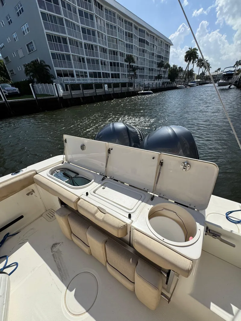 Slide: The Image of 2018 Key West Billistic 281 Center Console boat with open storage compartments, docked near waterfront buildings. - 37