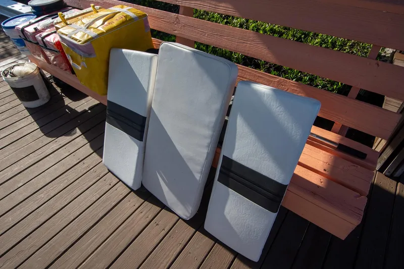 Slide: The Image of Cushions and supplies on a wooden deck, next to a bench, under sunlight. - 41