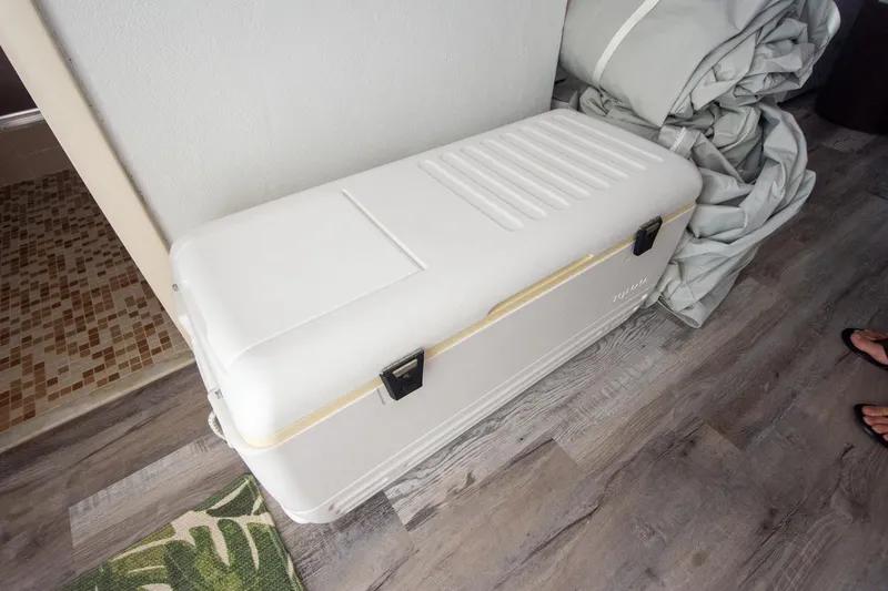 Slide: The Image of White cooler on wooden floor beside folded fabric, near a tiled area. - 42