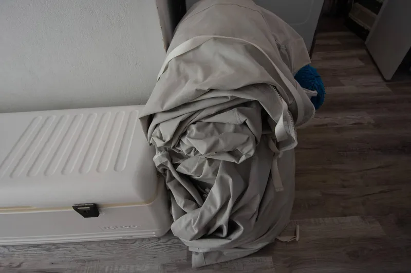 Slide: The Image of Rolled-up tarp beside a white cooler on wooden floor, indoors. - 43