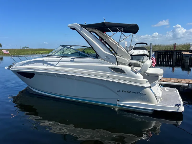 Slide: The Image of 2022 Regal 28 Express boat docked on calm water under a clear blue sky. - 1