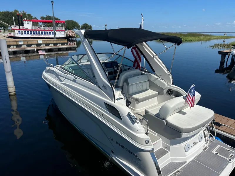 Slide: The Image of 2022 Regal 28 Express boat docked by a river with American flags. - 2